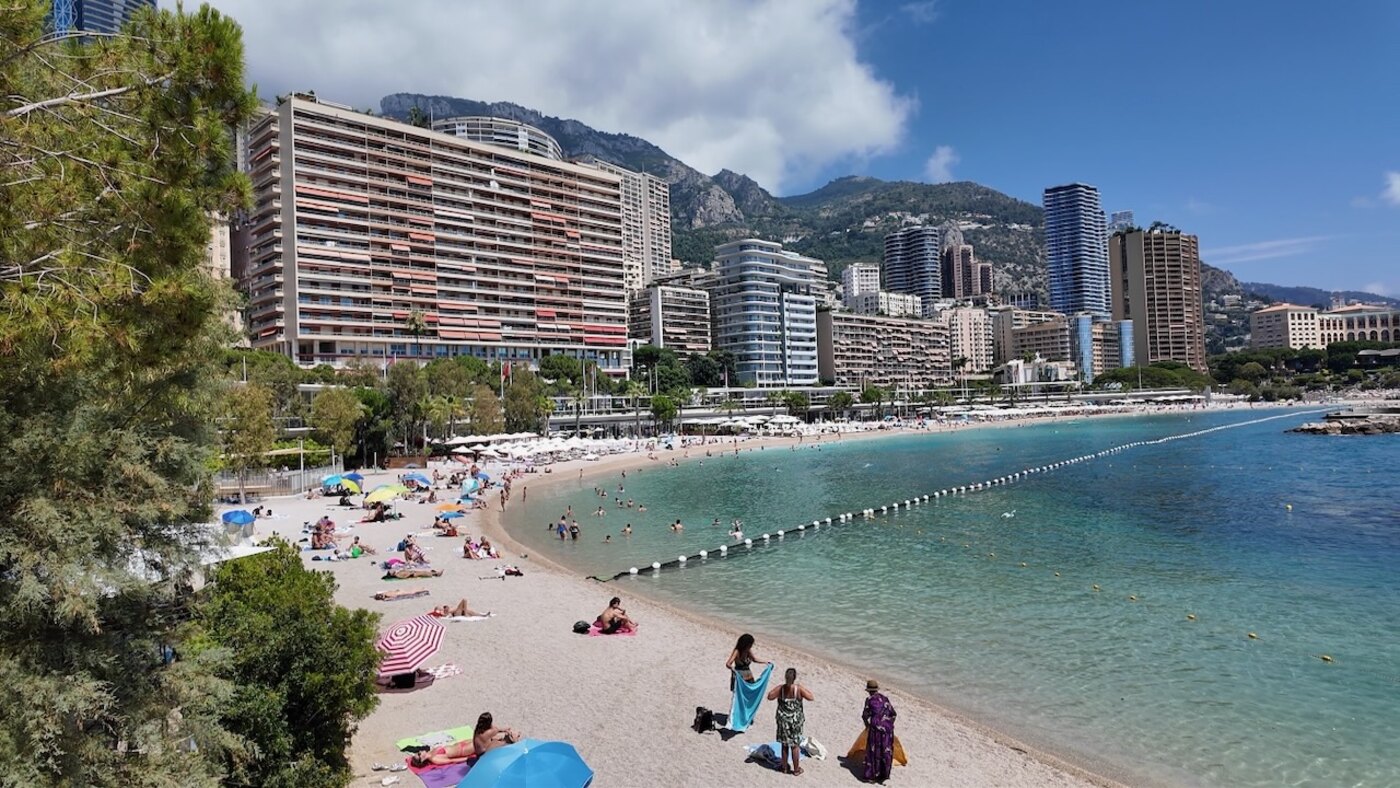 Larvotton hiekkaranta Monacossa, turkoosi meri ja rantautuneita ihmisiä